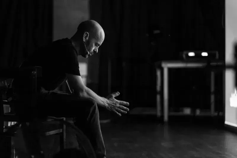 Rob Draper behind the stage, sitting on a chair and focusing for his upcoming talk