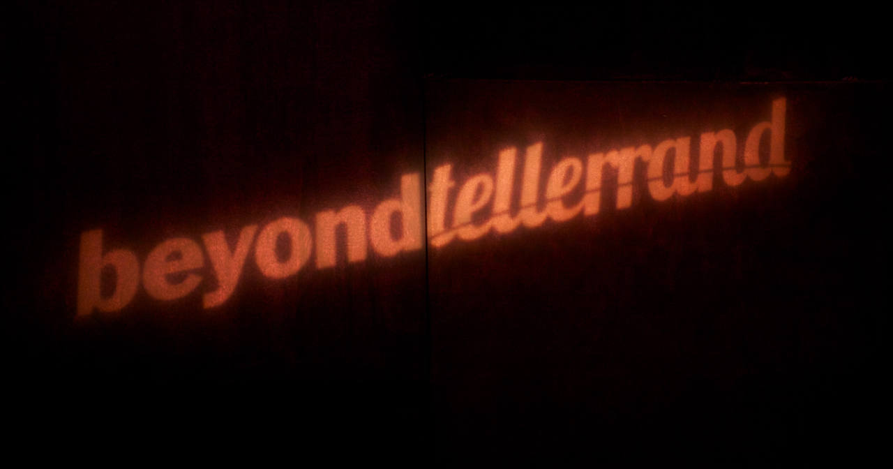 The beyond tellerrand logo from our first event in 2011 as a light projection in on a red wall in the theatre.