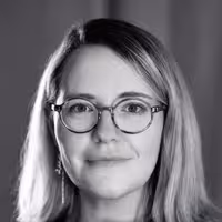 A portrait of Geri Coady. She wears glasses and firmly smiles into the camera