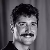 Portrait photo of Abel Reverter. He smiles and looks into the camera, wearing a black shirt.