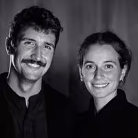 A portrait of Abel Reverter on the right and Katie Menzies on the left. Together they are known as Cabeza Patata, a design studio. Both are happily smiling into the camera