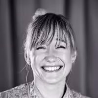 This is a portrait photo of Linda Liukas. She looks into the camera and has a big smile on her face. Looks very happy.