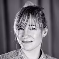 A portrait photo of Linda Liukas. She grins and has her head slightly bended to the left.